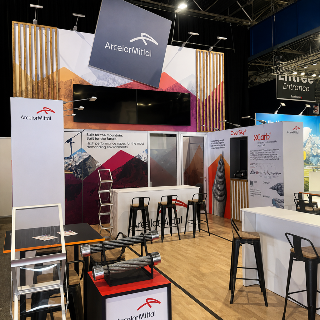 Stand ArcelorMittal Mountain Planet 2026 — podiums de présentation câbles et comptoir réceptif, univers montagne
